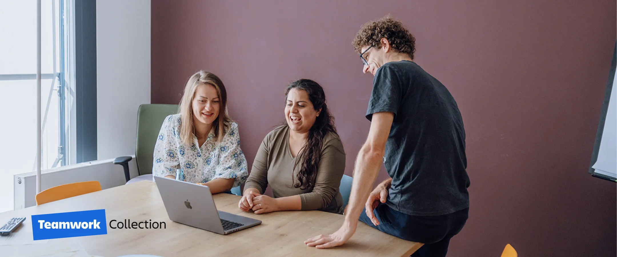 three people sitting at a table looking at a laptop screen