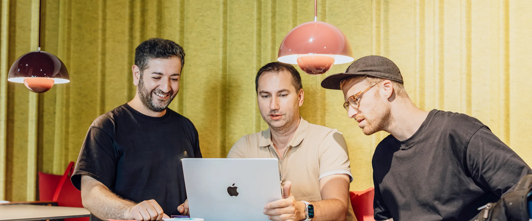 Three colleagues reviewing AI model options together on a laptop in a modern office