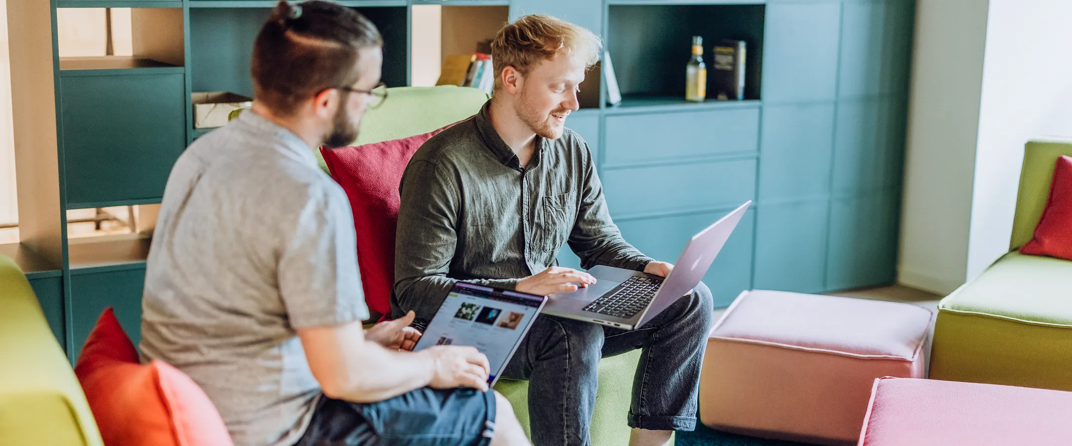 two people smiling and talking with a laptop