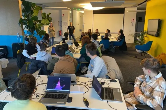 Students from Oranienschule Wiesbaden at the Seibert Group programming days, working on laptops at group tables.