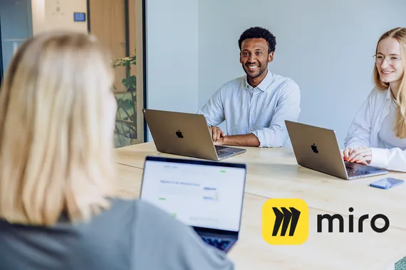two employees drinking a coffee and holding a virtual meeting on Google Meet with the Miro logo in the foreground