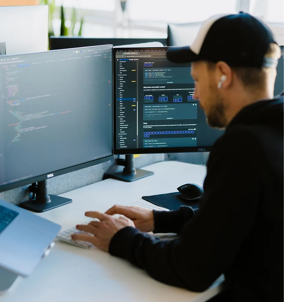 Developer working on a dual-monitor setup with code and design tooling open